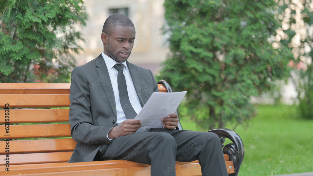 African Businessman Reading Documents while Sitting Outdoor African Businessman Reading Documents while Sitting Outdoor