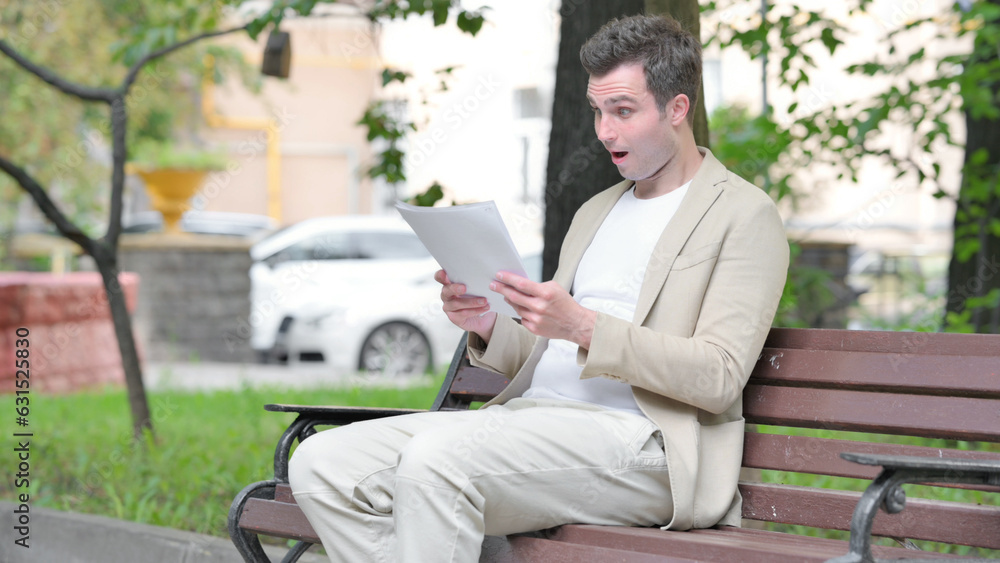 Fototapeta premium Casual Young Man Celebrating while Reading Documents Outdoor