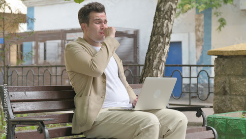 Coughing Young Man Using Laptop Outdoor