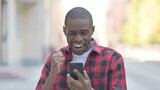 African American Man Celebrating Success on Smartphone Outdoor