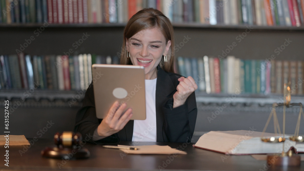 Young Female Lawyer Celebrating Success on Tablet in Office Young Female Lawyer Celebrating Success on Tablet in Office