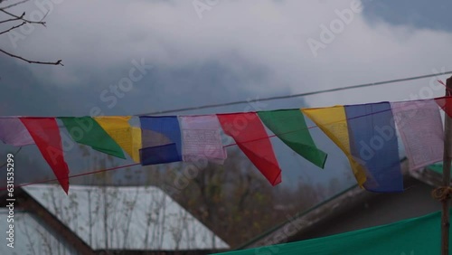 Closeup slow motion shot of Buddhist prayer flags waving in the wind with mountain peaks covered by snow at Manali in Himachal Pradesh, India. Prayer flags in front of mountains during winter season.	