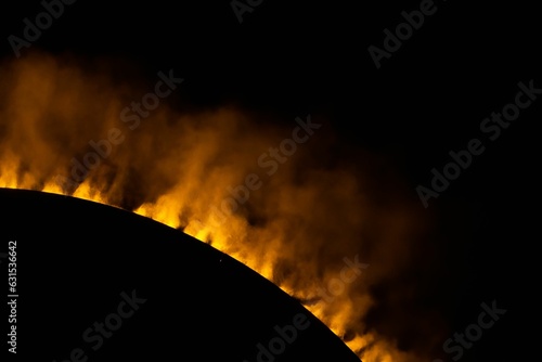 a large flame with some clouds over it and a black background photo