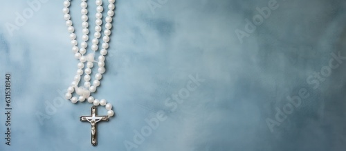 A white canvas with a painted background displaying a blue-beaded rosary, viewed from the top, © HN Works