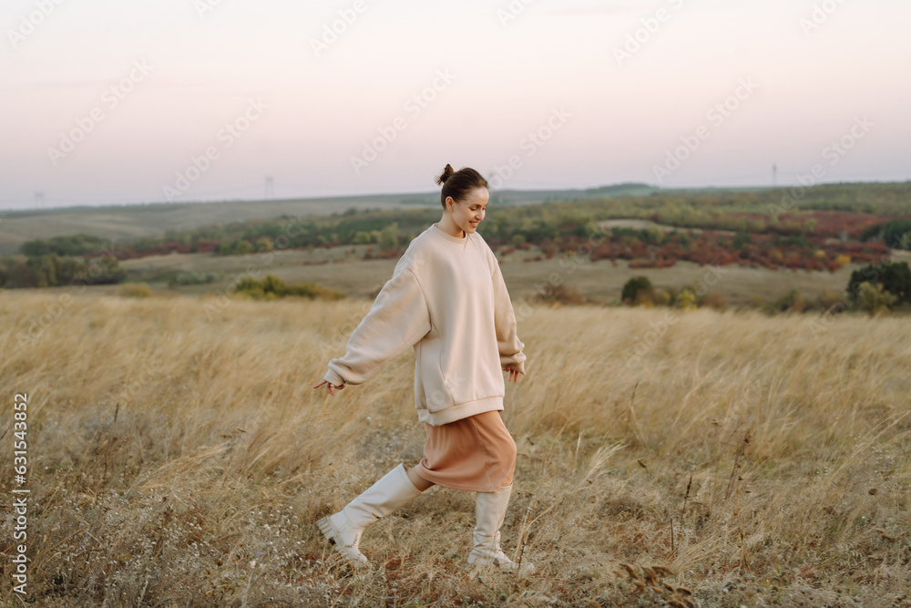 Beautiful model in stylish clothes posing on the autumn field. Fashion concept. Lifestyle, recreation.