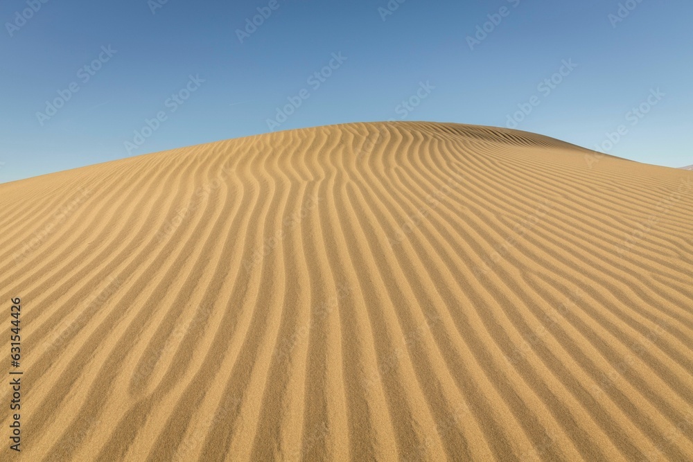 Vast expanse of golden sand with a deep blue sky in the background