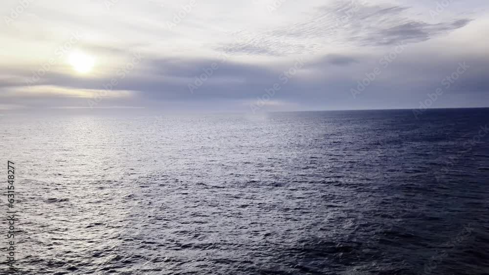 Aerial of the calm ocean under the cloudy sky with the horizon in the background Aerial of the calm ocean under the cloudy sky with the horizon in the background