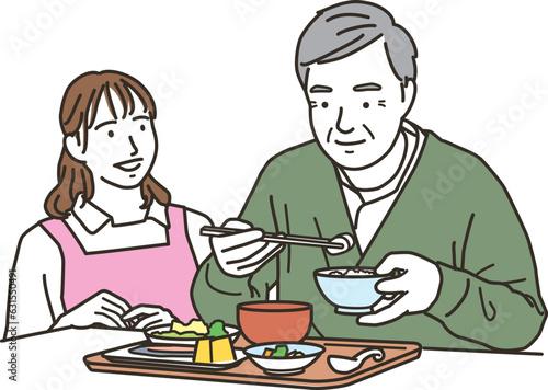 食事介助をする女性の介護士と高齢者男性
