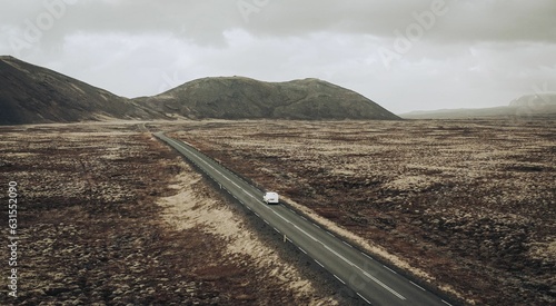 Aerial view of a car driving on a road in an expansive grassland landscape photo