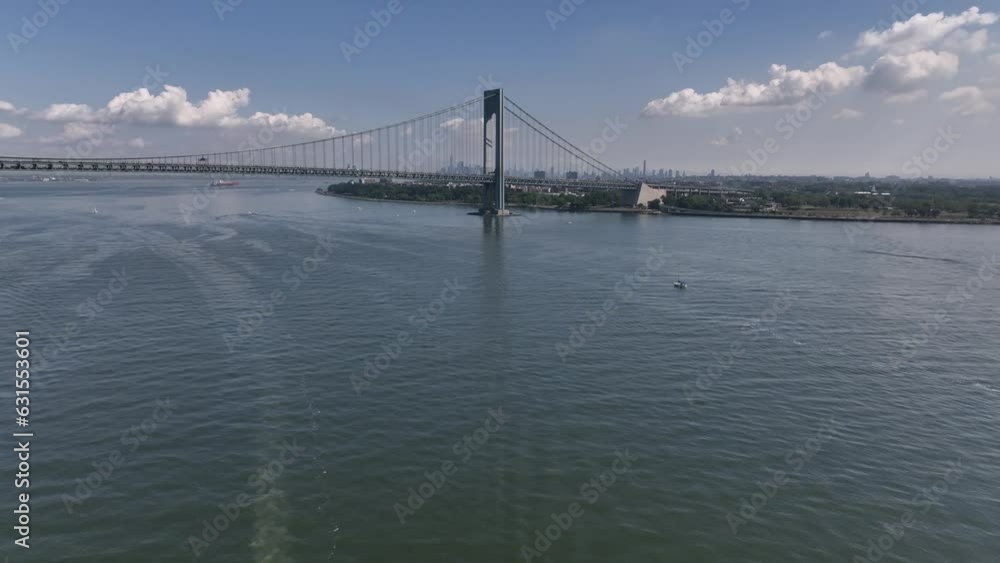 Aerial video of a boat in the deep blue sea with a bridge in the background Aerial video of a boat in the deep blue sea with a bridge in the background