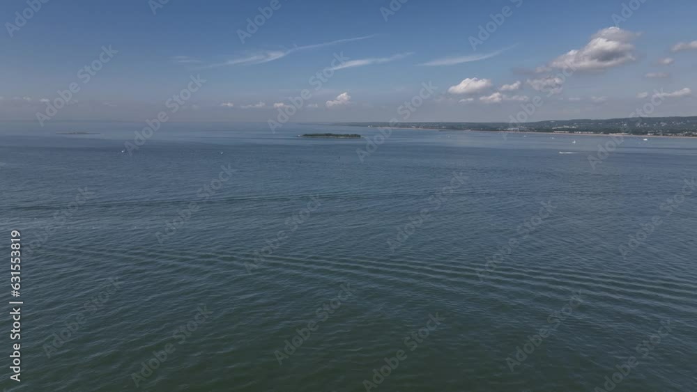 Aerial video of a boat in the deep blue sea with a shore in the background Aerial video of a boat in the deep blue sea with a shore in the background