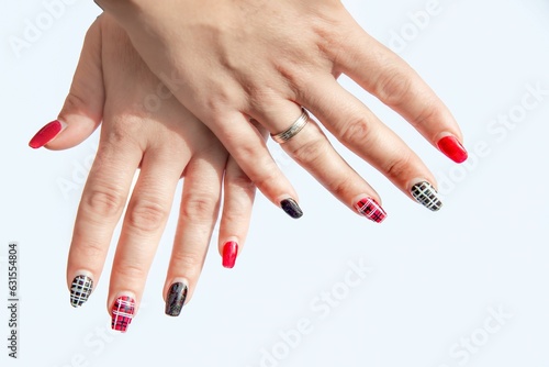 Woman s two hands with red and black checkered designs painted on the fingernails.