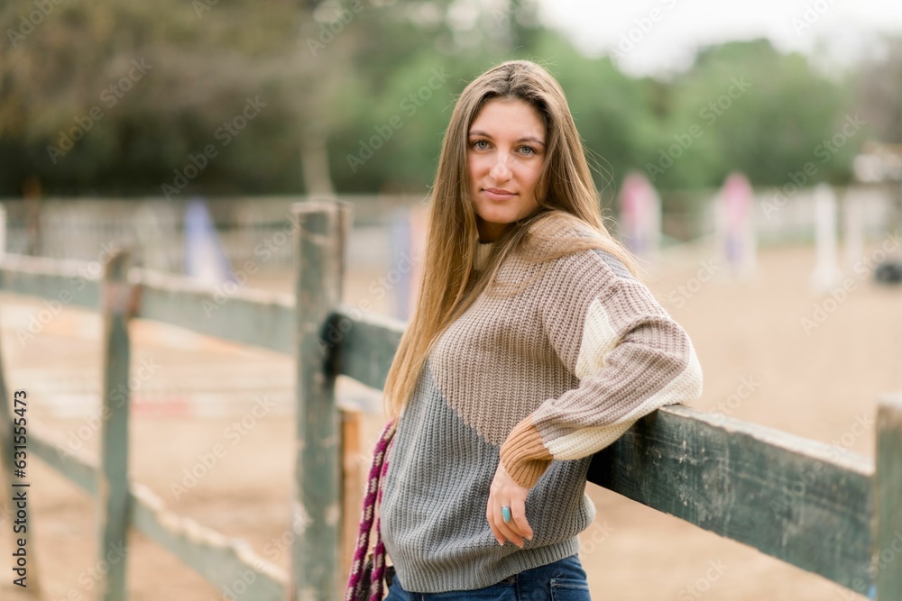 Young girl posing against a fence in a horse barn Young girl posing against a fence in a horse barn