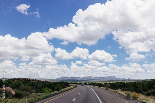 Beautiful summer landscape with highway among rocky mountains and blue sky with fluffy clouds on a summer day. Roadscape in New Mexico near Albuquerque, USA
