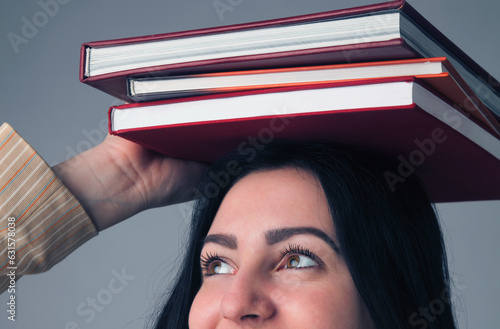 Knowledge,  self development and education concept. Portrait of young student girl balancing books on her head. Horizontal image.