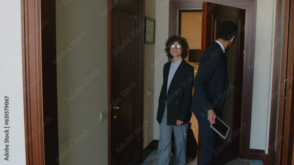 Medium long shot of hotel manager holding digital tablet in his hands, showing room for female guest Medium long shot of hotel manager holding digital tablet in his hands, showing room for female guest
