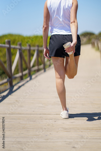 Anonymous woman in sportswear standing with one leg and exercising