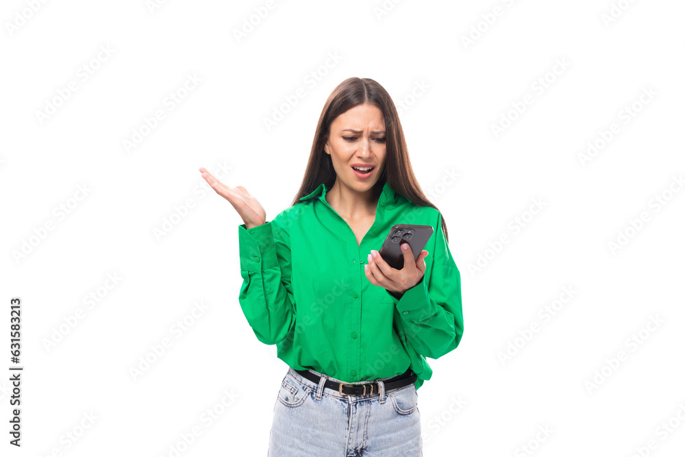 pretty well-groomed brunette long-haired young woman in a green shirt chatting online in the phone on a white background with copy space pretty well-groomed brunette long-haired young woman in a green shirt chatting online in the phone on a white background with copy space