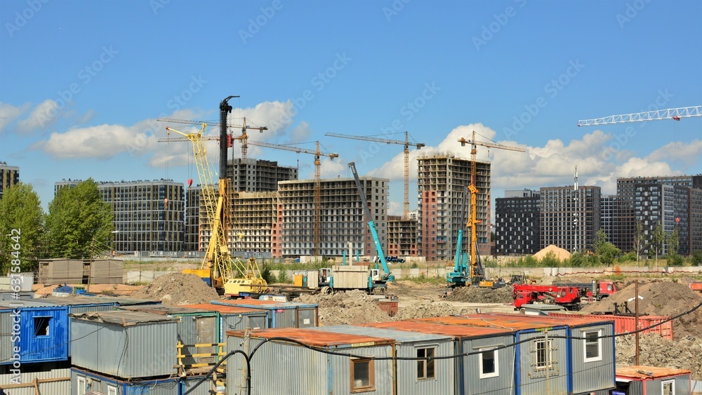 Construction site and construction city near the development of new residential buildings: building frames, construction machinery, tower cranes, сonstruction trailers.