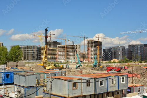 Construction site and construction city near the development of new residential buildings: building frames, construction machinery, tower cranes, сonstruction trailers.