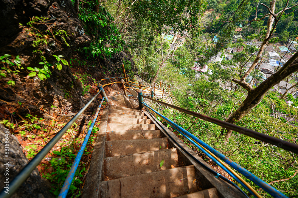 Fototapeta premium Steep stairs climbing up a limestone karst cliff through the rainforest to the mountaintop pagoda of the Wat Tham Suea aka the Tiger Cave Temple of Krabi in the south of Thailand