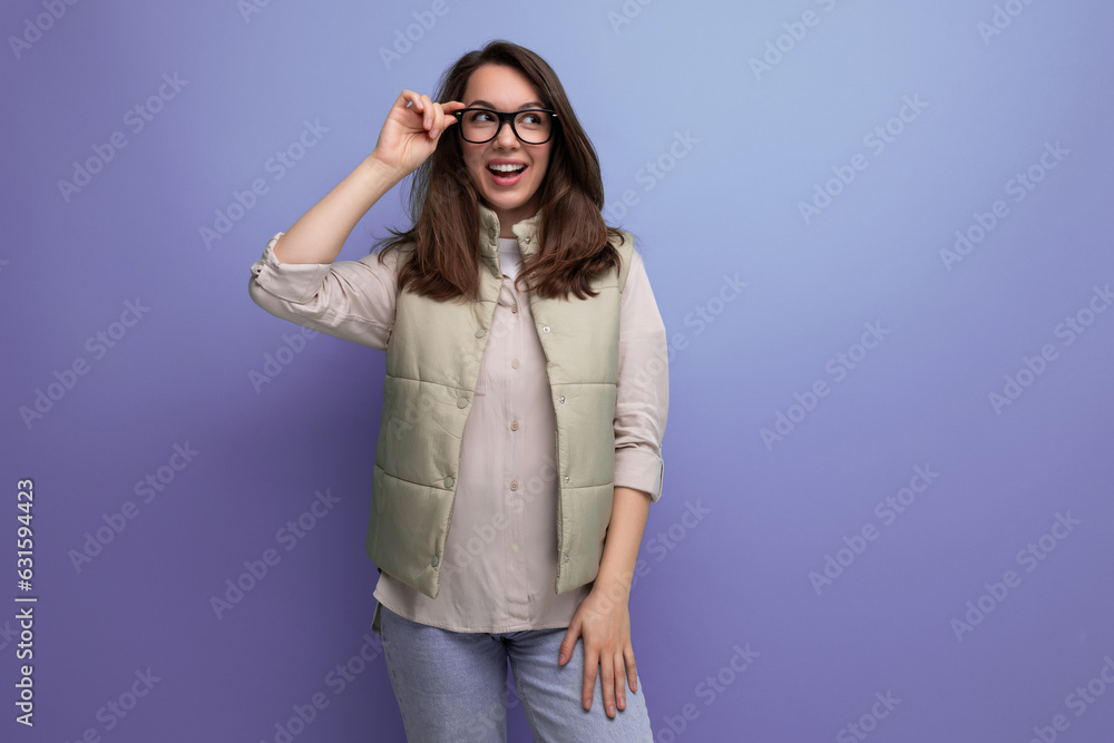 positive young brunette businesswoman with black rimmed glasses on studio background with copy space