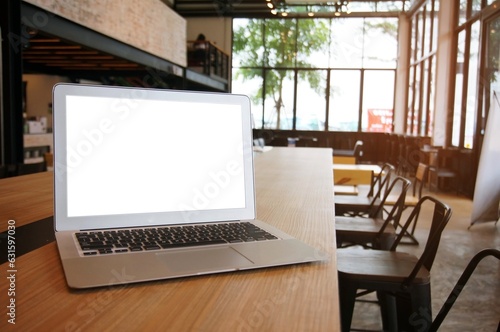 Laptop with Mock up blank screen on wooden table in front of coffeeshop cafe space for text. product display montage- technology concept