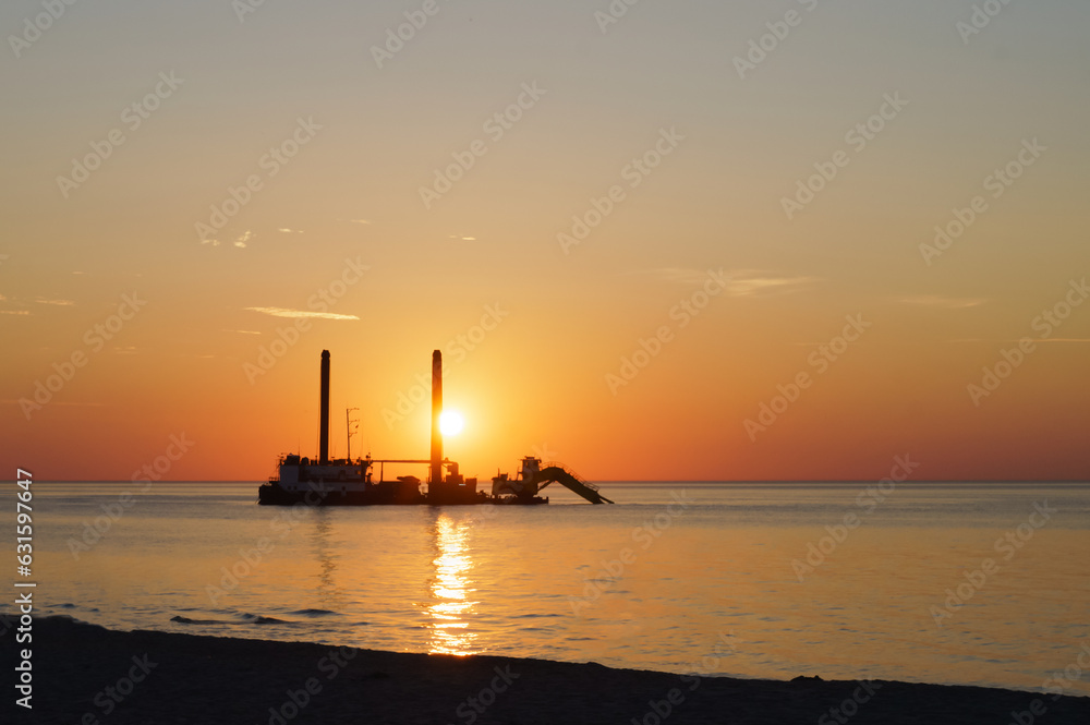 Dredging vessel. Sunset at sea and cleaning the fairway. The technique deepens the seabed.