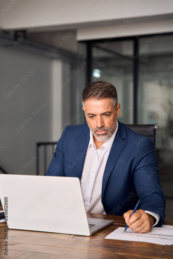 Vertical portrait of middle-age Hispanic man using laptop for business studying, watch online virtual webinar training, video call meeting. Focused mature Indian or Latin businessman work in office. Vertical portrait of middle-age Hispanic man using laptop for business studying, watch online virtual webinar training, video call meeting. Focused mature Indian or Latin businessman work in office.