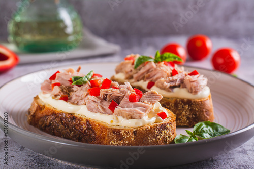 Open sandwiches with canned tuna, pepper and basil on cream cheese on a plate