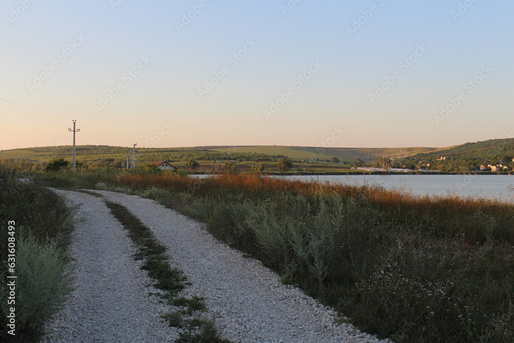 A gravel road next to a body of water