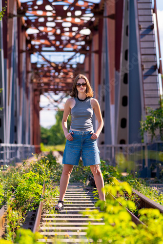 Obraz na płótnie Young woman looking at the camera while standing on a bridge w salonie