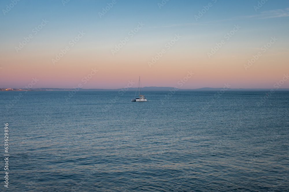 Aerial view of a sailboat in the sea at sunset in Cascais, Portugal 