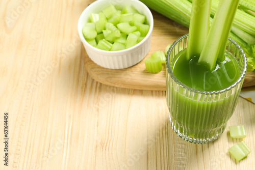 Glass of celery juice and fresh vegetables on wooden table. Space for text