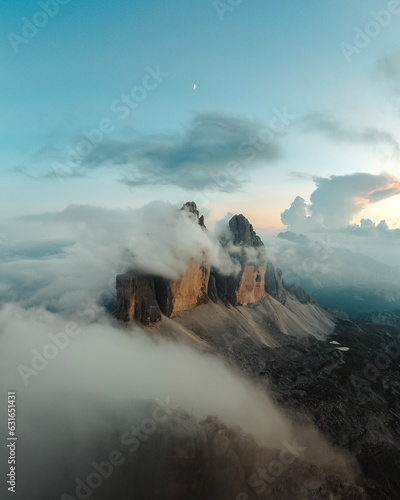 Majestic Tre Cime di Lavaredo being revealed in a dramatic light with low clouds and mist.