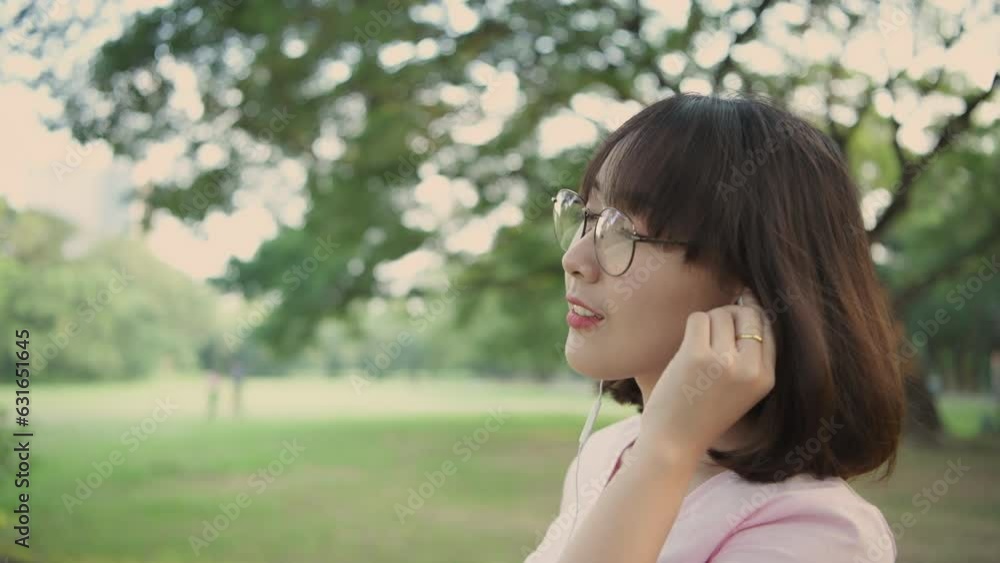 Holiday concept of 4k Resolution. Asian woman wearing headphones in the garden. she is listening to music online. Holiday concept of 4k Resolution. Asian woman wearing headphones in the garden. she is listening to music online.