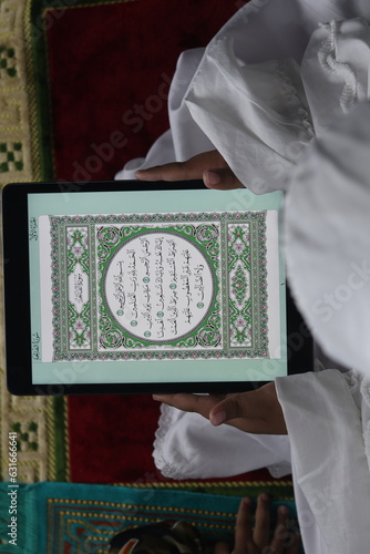 Muslim girl reading electronic Quran on tablet
 photo