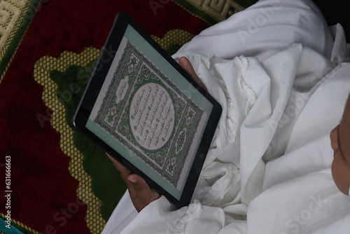 Muslim girl reading electronic Quran on tablet
 photo