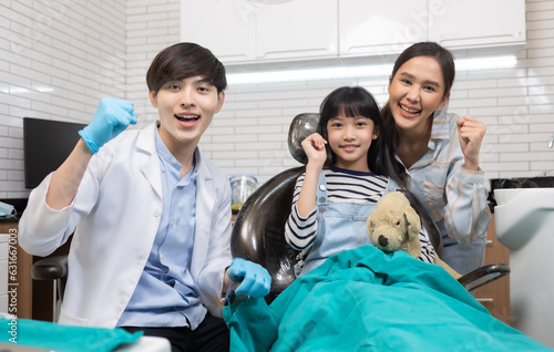 Children s dentistry for healthy teeth .Close-up  happy little child asian girl smiles looking at camera  sitting in dentist s chair  receiving dental.