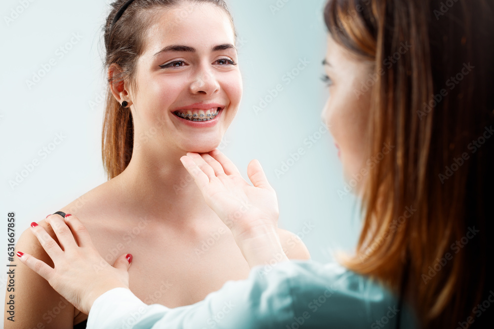 Girl smiles, shows braces; dentist checks with expertise Girl smiles, shows braces; dentist checks with expertise