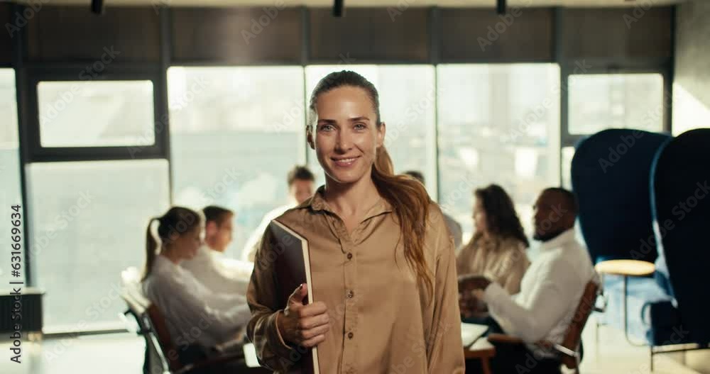 Confident happy girl in business office clothes holding a tablet in her hands, smiling and looking at the camera in the office Confident happy girl in business office clothes holding a tablet in her hands, smiling and looking at the camera in the office