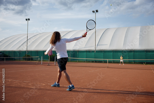 Young sports woman and man playing tennis on outdoor court © Nomad_Soul