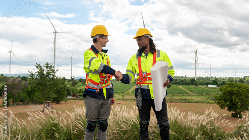  Smart engineers with protective helmet shaking hands at electrical turbines field