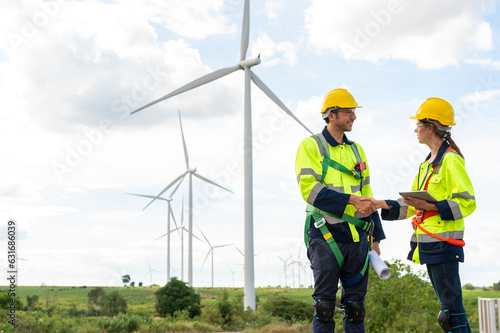  Smart engineers with protective helmet shaking hands at electrical turbines field