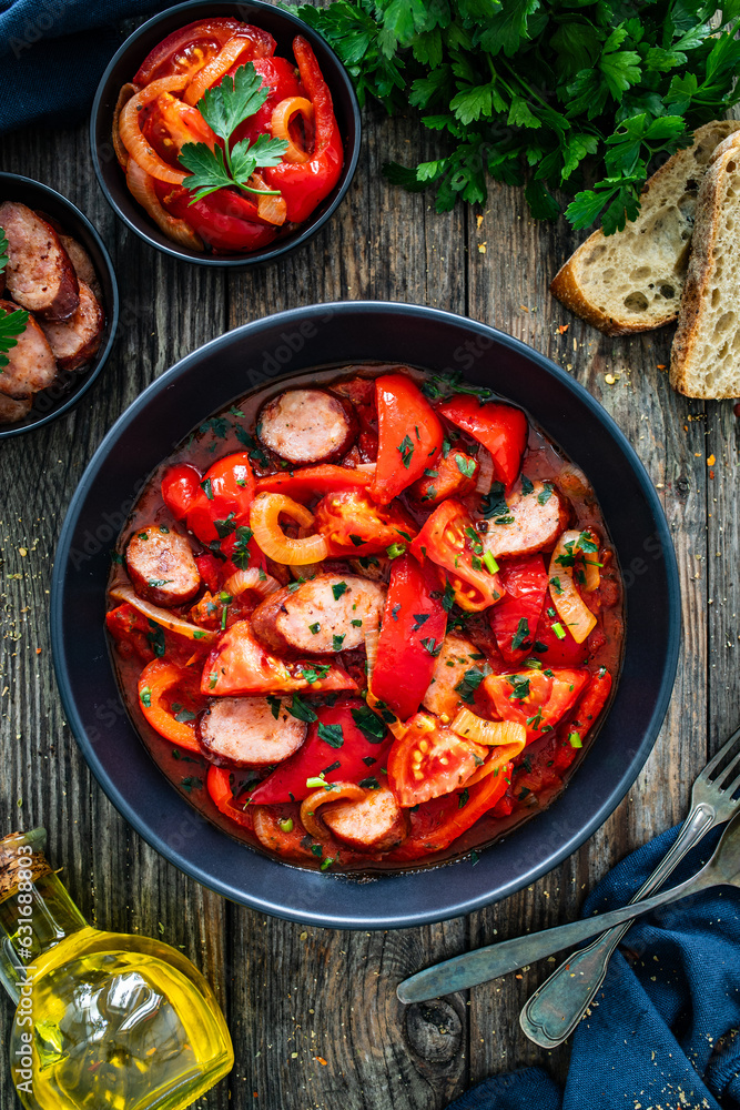 Delicious letcho - vegetables with sausages on wooden table
Delicious letcho - vegetables with sausages on wooden table