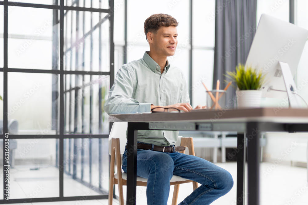 Portrait of young businessman sitting at his desk in the office. Portrait of young businessman sitting at his desk in the office.