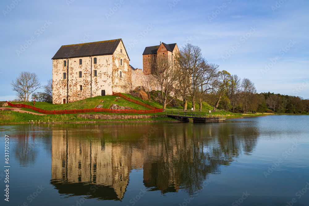 Medieval Kastelholm Castle and its reflections on a calm river in Åland Islands, Finland, on a sunny day in the summer.