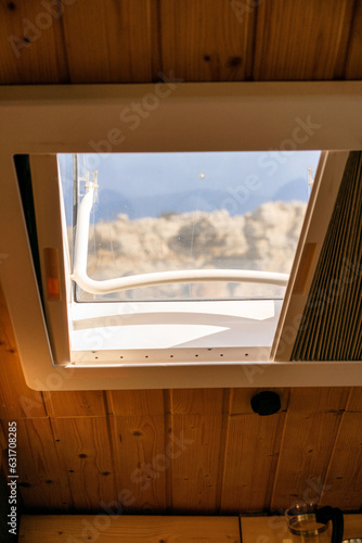 Interior of a camper van with a mountain view through the skylight window