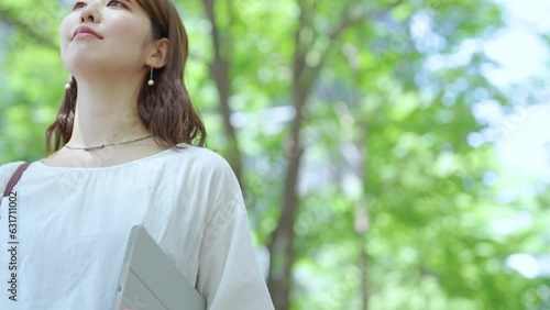緑のある街並みを歩く女性