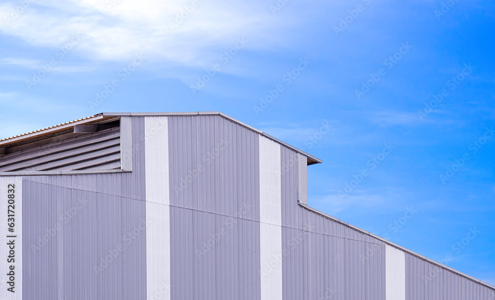 Gray and white corrugated metal wall with louver and rooftop of modern industrial building against blue sky background, perspective side view Gray and white corrugated metal wall with louver and rooftop of modern industrial building against blue sky background, perspective side view